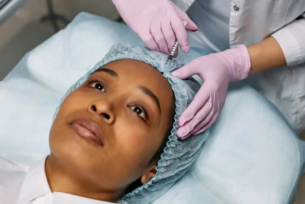 Patient lying on a treatment bed while a clinician examines their scalp